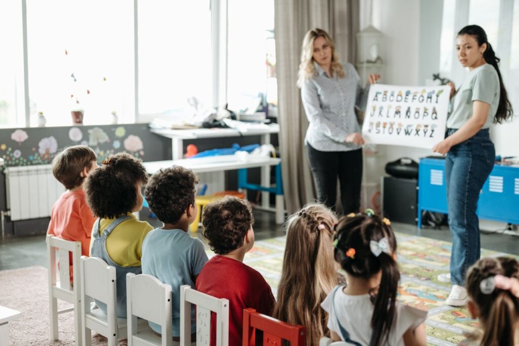 Teachers engage children in learning alphabet during a kindergarten class.